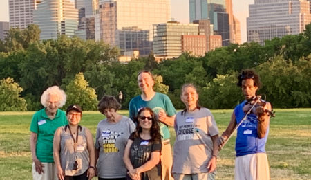 7 people standing in a field, with the skyline of Minneapolis